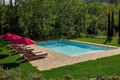 a swimming pool with chairs and umbrellas in a yard at Villa Mandorla by My Villa Collection in Badia A Passignano