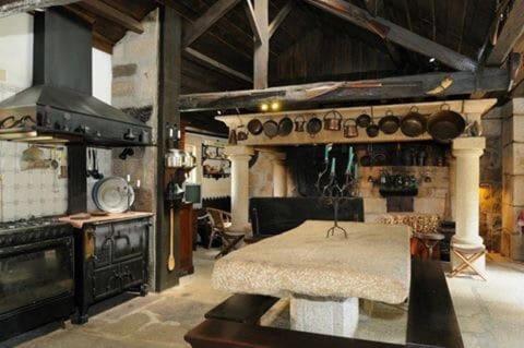 a kitchen with a stove and a table in a room at Casa do Barreiro de Cima in Mondim de Basto