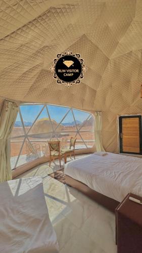 a room with two beds and a table and a view of the desert at RUM FLOWER lUXURY CAMP in Disah