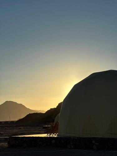a tent with the sun setting in the background at RUM FLOWER lUXURY CAMP in Disah