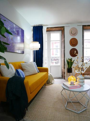 a living room with a yellow couch and a table at Vivienda pleno corazón de la ciudad, As rías in A Coruña