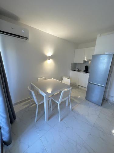 La cuisine est équipée d'une table et de chaises blanches ainsi que d'un réfrigérateur. dans l'établissement Résidence Graziella Studio 406, à Juan-les-Pins