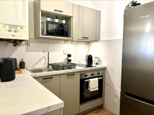 a kitchen with a stainless steel refrigerator and a sink at KLEBER- charmant T2 proche gare in Saint-Brieuc