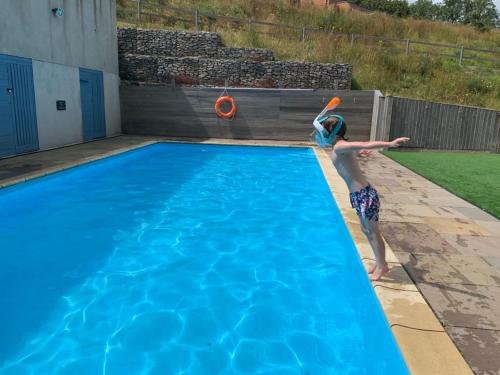 a person playing with a frisbee in a swimming pool at Avocet 2 Luxury Apartment with Pool and Parking in Brixham