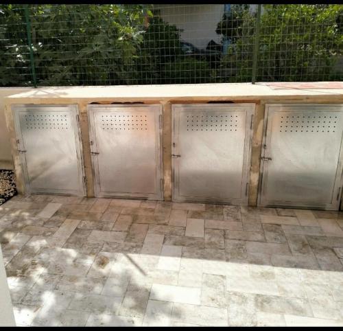 a row of four metal doors on a patio at Kevin ' s house in Posada