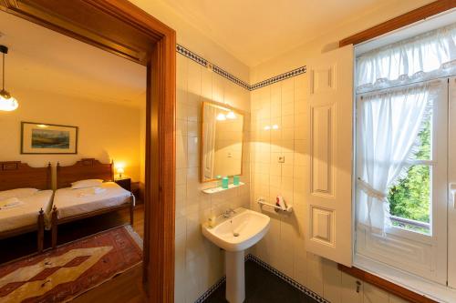 a bathroom with a sink and a bed and a window at Casa de Valdemar in Felgueiras