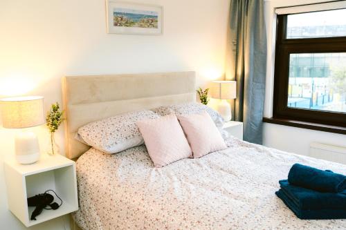 a bedroom with a bed with pink pillows and a window at City Centre - Free Parking - 2 Bedroom in Belfast