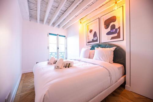 une chambre avec un grand lit blanc avec deux serviettes dessus dans l'établissement CIA - flat in Paris Louvre museum with balcony, à Paris
