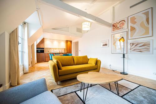 un salon avec un canapé jaune et une table dans l'établissement CIA - flat in Paris Louvre museum with balcony, à Paris