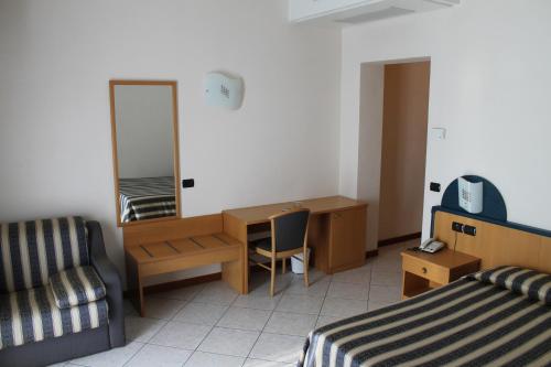 a hotel room with a bed and a desk and a mirror at Albergo Villa Eva in Costermano sul Garda