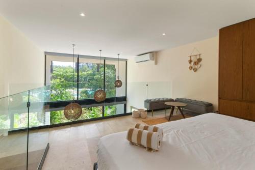 a bedroom with a bed and a glass wall at Loft Hermosa at Tulum's Mistiq Temple II Beaches in Tulum