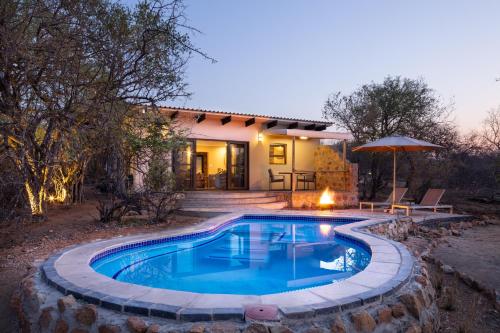 a swimming pool in front of a house at Oase by 7 Star Lodges - Greater Kruger Private 530ha Reserve in Hoedspruit