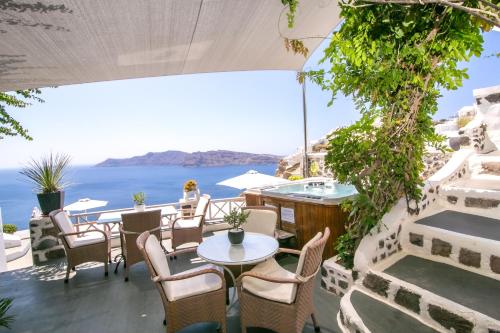 a patio with tables and chairs and a view of the ocean at Alexander's Suites in Oia