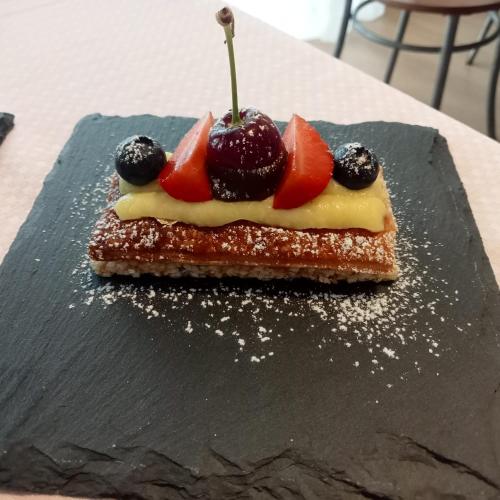a piece of cake with fruit on a black plate at SANTINO'S HOUSE in Peveragno