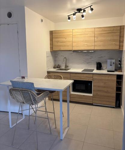 une cuisine avec une table blanche et deux chaises dans l'établissement Superbe studio tendance et zen proche de Lyon, à Couzon-au-Mont-dʼOr