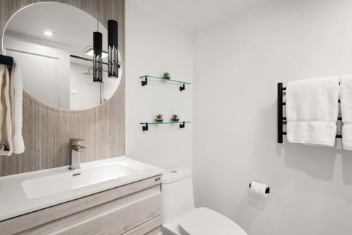 a white bathroom with a sink and a mirror at Fully Renovated 2 BR on River with Pool - Walk to Town! in Aspen