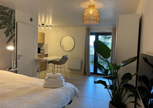 - une chambre avec un lit, une table et une plante dans l'établissement Superbe studio tendance et zen proche de Lyon, à Couzon-au-Mont-dʼOr