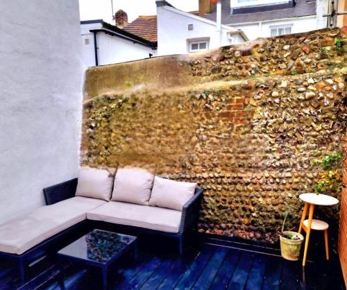 eine Couch auf einer Terrasse neben einer Wand in der Unterkunft Brighton Cottage By The Sea in Brighton & Hove