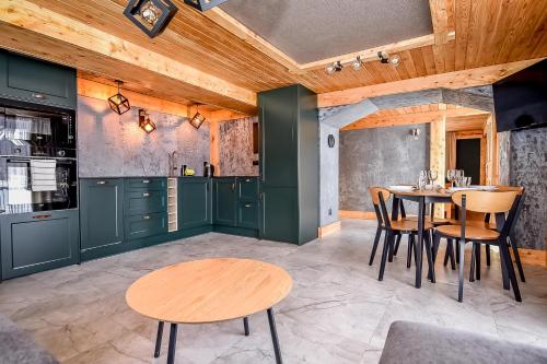 a kitchen with green cabinets and a table and chairs at Apartament Hanka z Jacuzzi i widokiem na góry in Zakopane