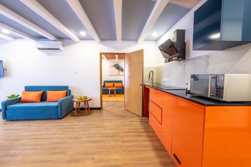 a kitchen with orange cabinets and a blue couch at Kingfisher Nest Hotel Suites- Westlands, Near Sarit Center in Nairobi