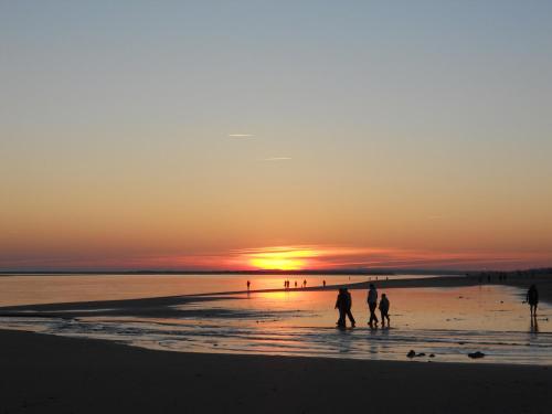 a group of people walking on the beach at sunset at Apartamento acogedor El portil in El Portil