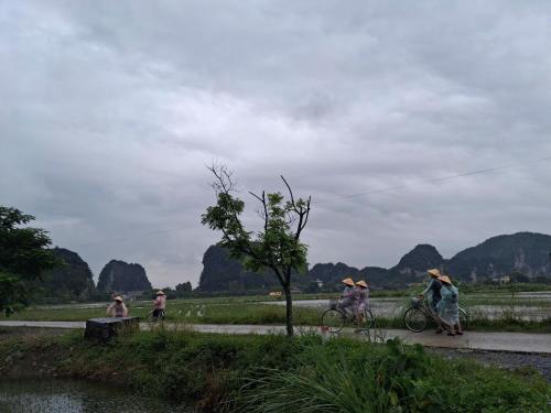 a group of people riding bikes on a path near a river at Tam Coc Moutainside Homestay in Ninh Binh