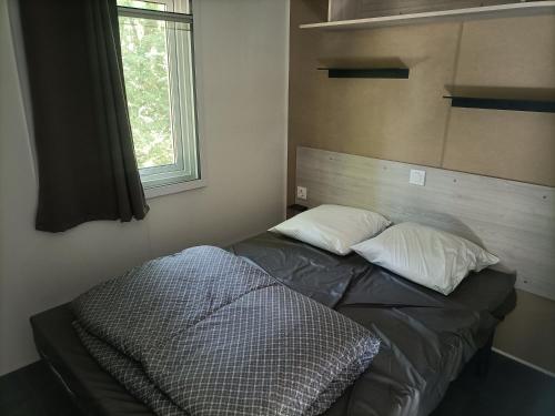 a bed in a room with two pillows and a window at Camping de la Croix d'Arles in Bourg