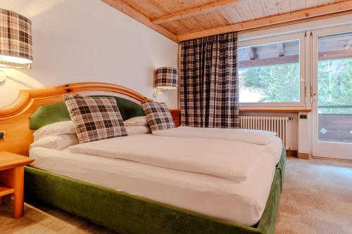 a bedroom with a bed and a large window at Sporthotel Teresa in Badia
