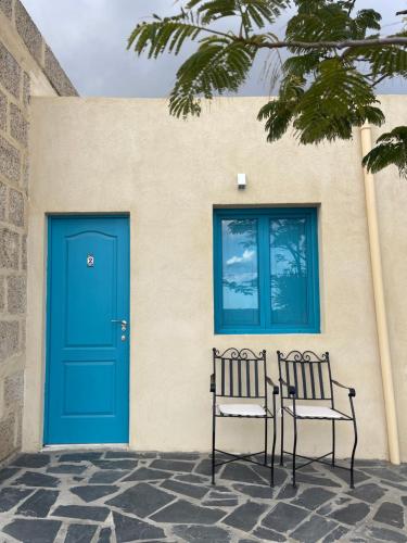 two chairs sitting in front of a building with a blue door at Las Cuevas - 3 bed finca in a serene setting in Santa Cruz de Tenerife