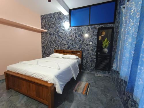 a bedroom with a bed and a blue wall at Amruth Homestay Honavar room 1 in Honāvar