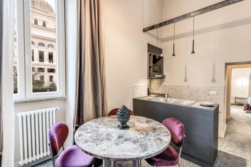 a kitchen with a table and some purple chairs at Palazzo Ottavia - La Maison D'art Collection in Rome