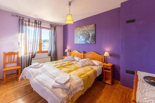 una camera con pareti viola e un grande letto di Casa del Tio Primitivo a Navarredonda de Gredos