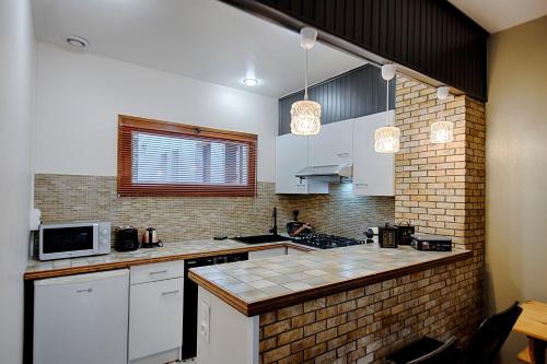 une cuisine avec des placards blancs et un mur en briques dans l'établissement Les Cantinières - Bourgoin Jallieu - Jardin Privé, à Ruy