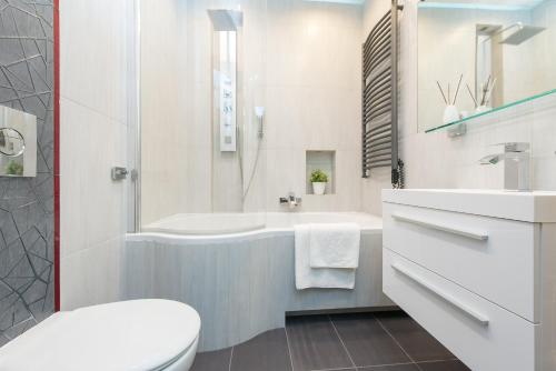 a bathroom with a tub and a toilet and a sink at Old Town Square P&O Apartments in Warsaw