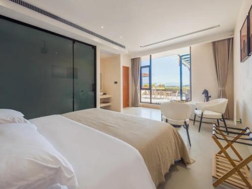a bedroom with a white bed and a table and chairs at Dali Jiujing Inn in Dali
