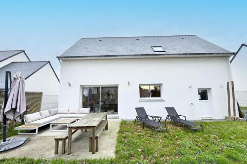 une maison blanche avec une table de pique-nique et des chaises dans l'établissement Maison contemporaine tout confort -5min des plages, à Kervignac