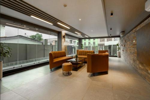a lobby with leather chairs and tables and windows at ila comfort in Bāglung