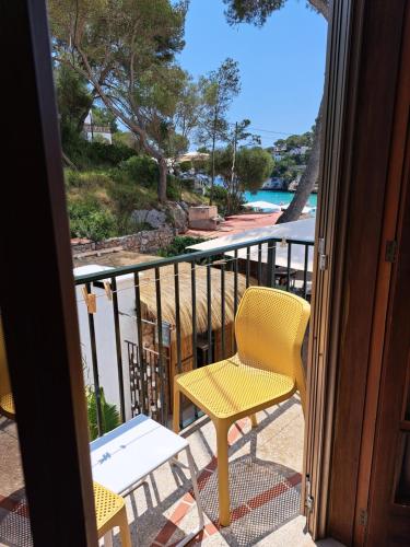 a yellow chair and a table on a balcony at Hostal Playa in Cala Santanyi