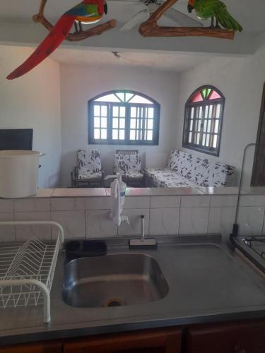 a kitchen with a sink and two windows at Chalés Monções in Ubatuba