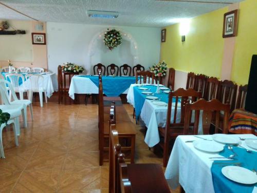 a dining room with tables and chairs with blue linens at Hostal Curiñan in Otavalo
