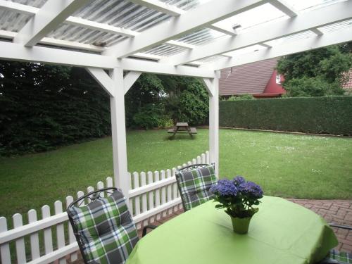 einen Tisch und Stühle unter einer weißen Pergola in der Unterkunft Busche RE03 in Sögel
