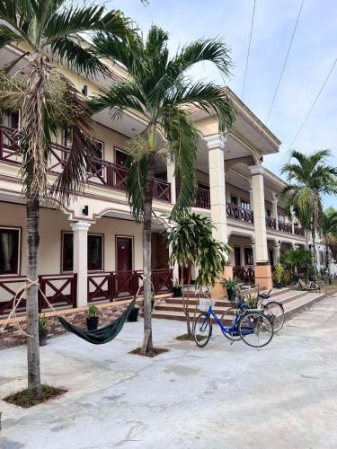 a building with palm trees and a hammock in front of it at Lebijou Guesthouse - Konesavath in Don Det