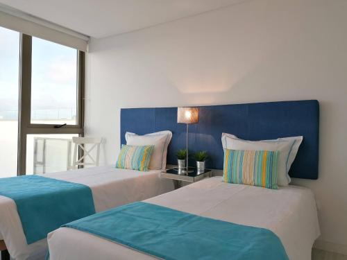 2 letti in una camera con testiera blu di Silver Coast Heights H ad Areia Branca