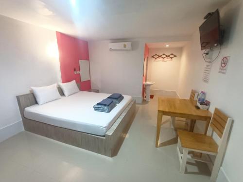 a small bedroom with a bed and a table at Saan Rak Resort in Prachuap Khiri Khan