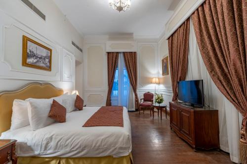a hotel room with a bed and a television at Maison Maxim De Lesseps in Ismailia