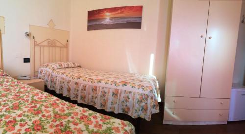 a hotel room with two beds and a dresser at Lungomare Hotel in Marina di Cecina