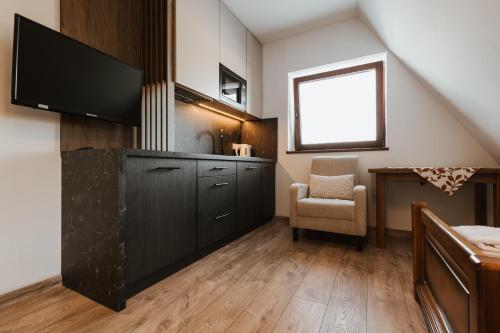 a living room with a tv and a chair at Dom Wypocz Pod Litwinką Apartamenty in Białka Tatrzanska
