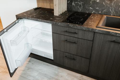 an open refrigerator in a kitchen with a sink at Dom Wypocz Pod Litwinką Apartamenty in Białka Tatrzanska