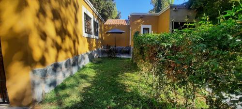 eine Gasse, die zu einem gelben Haus mit einem Regenschirm führt in der Unterkunft Mono ambiente Loria in Ciudad Lujan de Cuyo
