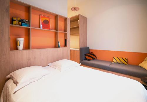 a bedroom with a white bed and an orange wall at CENTRAL Hôtel Lille Centre in Lille